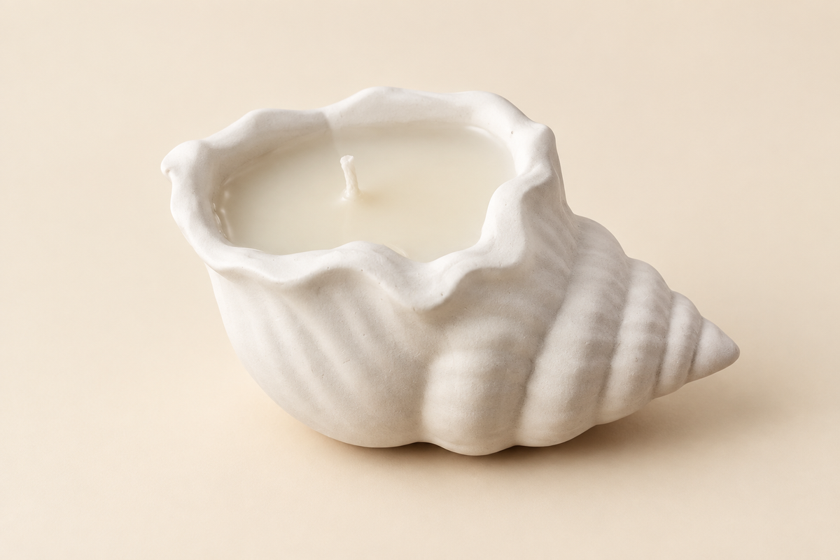 Bougie blanche en forme de coquillage spiralé, avec cire et mèche visibles, photographiée sur fond ivoire.
